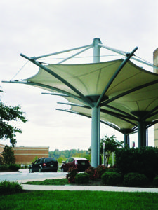 As a cost-saving alternative to a glass-and-steel entry canopy, this tensioned fabric canopy provides shade and internal rainwater drainage through inverted fabric cones. Curved tubular struts gently curve upward to shape the cones and help hold the fabric taut. Photo: Huntington Design Associates Inc.