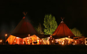 The peaks of Tentipi Stratus tents complement the surrounding tall trees. Ten tents were set up for a 40th birthday party in Hampshire, England. Photo: Tentipi AB