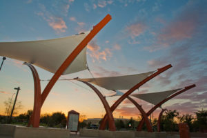 Commuters on the metro transit bus system in Mesa, Ariz., can appreciate the relief from the sun provided by the West Mesa Park and Ride. A dynamic crisscrossed row of curved red steel masts support the white fabric shade canopies over the bus passenger waiting platform. Photo: Eide Industries. 