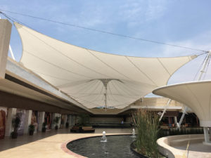 Like welcoming arms, a fabric shade canopy invites shoppers into the roof-top plaza of Cuernavaca Mall. A network of delicate but strong steel cables holds the fabric roof taut at cornice height. The cables feature three conical peaks that are thrust upward by “flying masts” suspended above the atrium on axis. Fabric is Sheerfill 1002 by Saint Gobain; design by Valarias DRV; fabrication White Sky. Photo: Courtesy Valarias DRV.