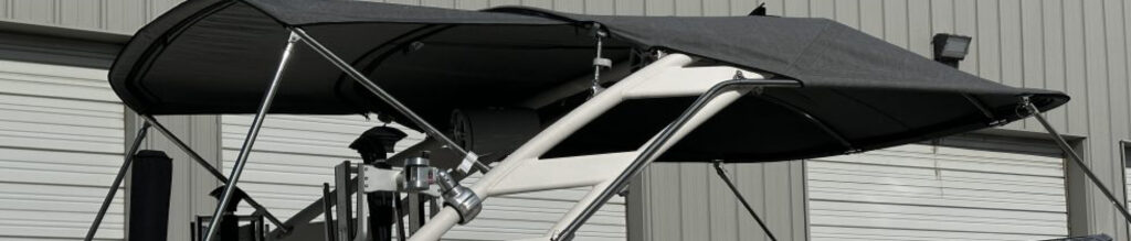 Black canopy supported by a white metallic frame, set against a gray building with closed roll-up doors.