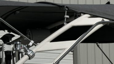 Black canopy supported by a white metallic frame, set against a gray building with closed roll-up doors.