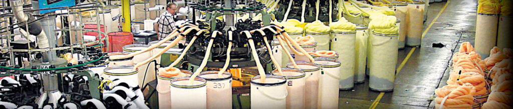 Manufacturing facility with spinning machinery and colorful spools; yellow, orange, and white materials arranged neatly, highlighting industrial processes.