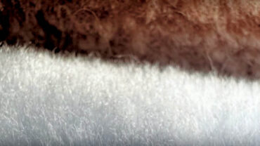 Close-up of textured, fluffy fabric in shades of brown and white, showcasing a blend of soft fibers and sustainable materials.
